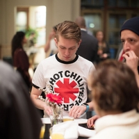 A person in a Red Hot Chili Peppers shirt standing at a small table, looking down at something
